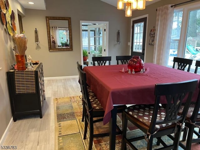 dining room with lofted ceiling, an inviting chandelier, and light hardwood / wood-style floors