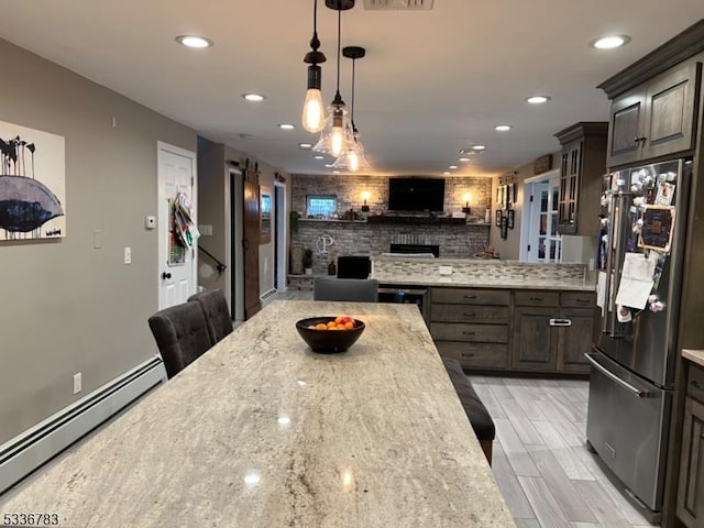 kitchen featuring dark brown cabinetry, a baseboard radiator, high quality fridge, and a kitchen breakfast bar