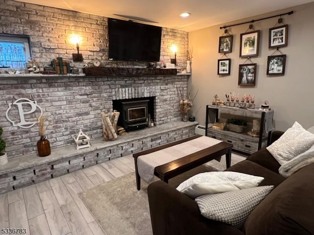 living room with brick wall, light hardwood / wood-style floors, and a wood stove