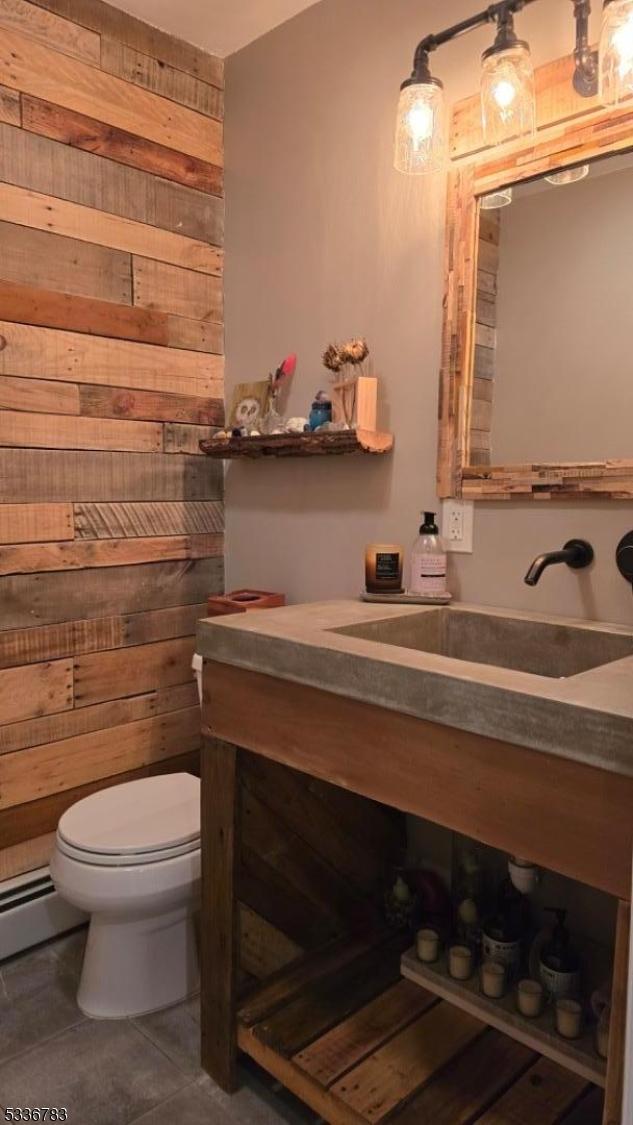 bathroom featuring wooden walls, tile patterned flooring, vanity, a baseboard heating unit, and toilet