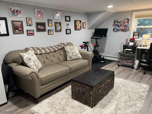 living room featuring crown molding, baseboard heating, and light hardwood / wood-style floors