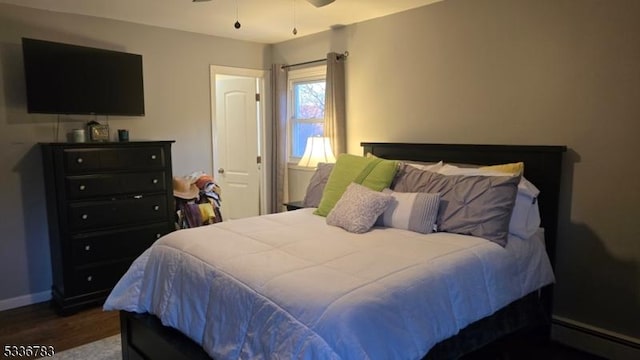 bedroom featuring dark wood-type flooring, ceiling fan, and a baseboard heating unit