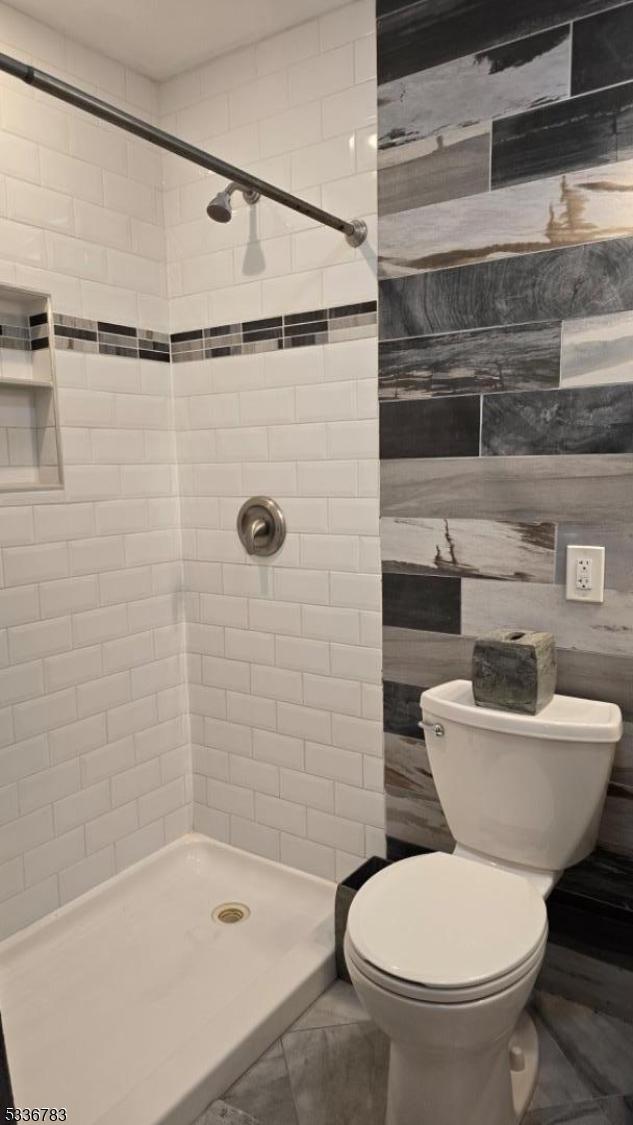 bathroom with tiled shower and toilet