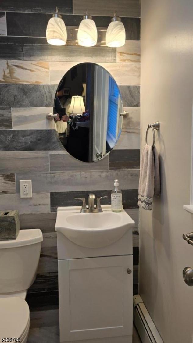 bathroom with vanity, a baseboard radiator, tasteful backsplash, and toilet