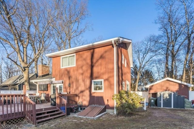 rear view of house featuring a wooden deck and a storage shed