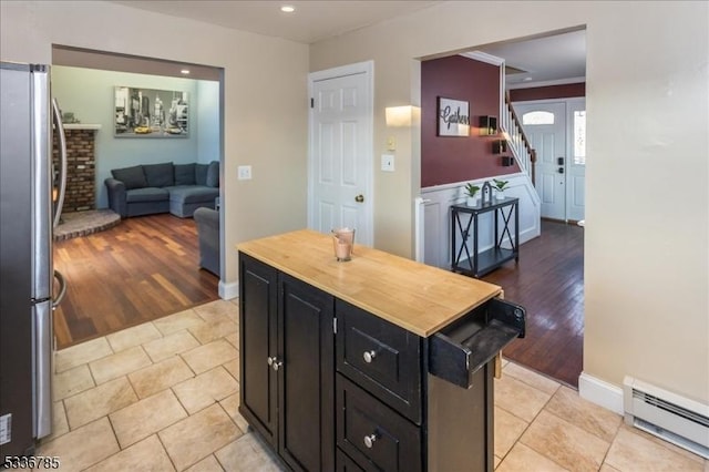 kitchen featuring a baseboard radiator, crown molding, stainless steel fridge, and light hardwood / wood-style floors