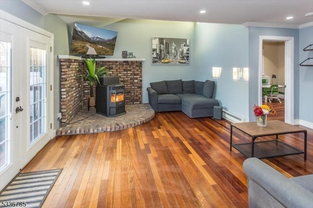 living room featuring hardwood / wood-style flooring, ornamental molding, baseboard heating, and a wood stove