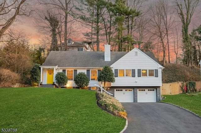 view of front of property featuring a chimney, fence, aphalt driveway, and a lawn