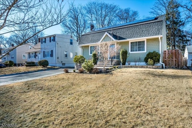 view of front of property with a front lawn and solar panels