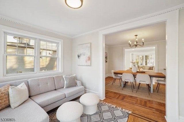 living room with a notable chandelier, ornamental molding, and parquet floors