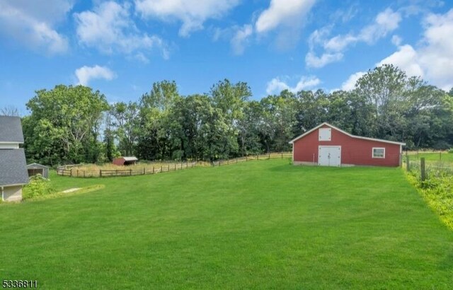 view of yard featuring a rural view, fence, and an outdoor structure