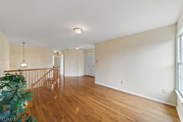 unfurnished room featuring an inviting chandelier and wood-type flooring