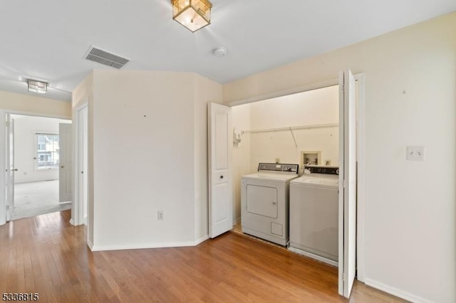 laundry area with light hardwood / wood-style floors and washing machine and dryer