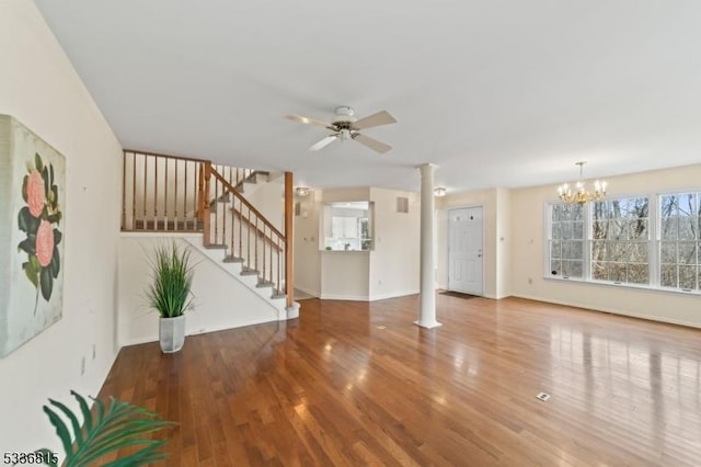 unfurnished living room featuring ornate columns, ceiling fan with notable chandelier, and hardwood / wood-style floors