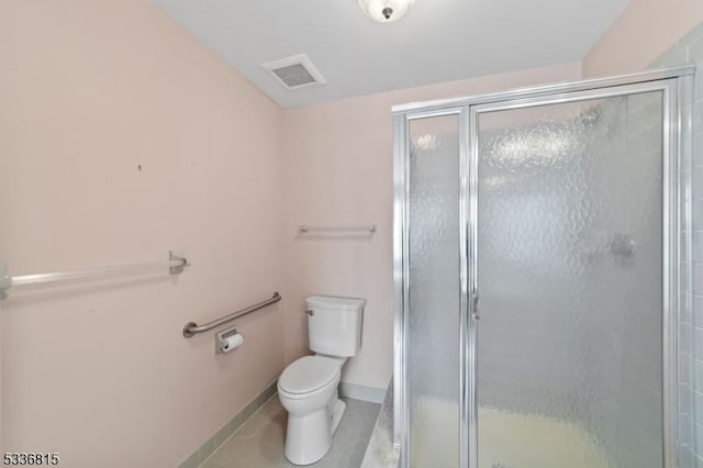 bathroom featuring tile patterned flooring, a shower with shower door, and toilet