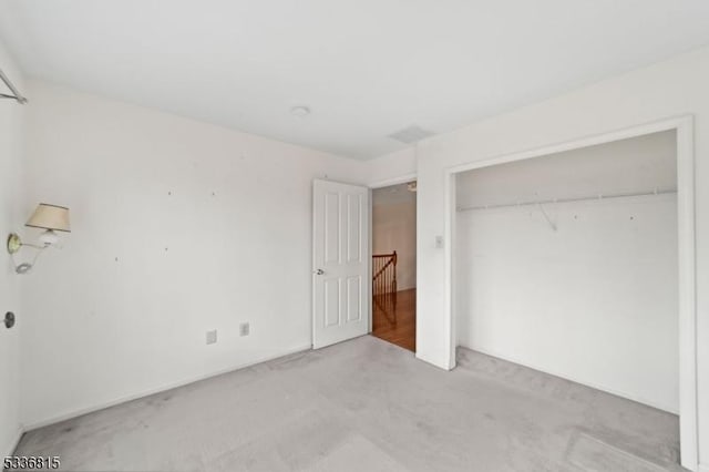 unfurnished bedroom featuring light colored carpet and a closet