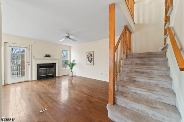 staircase with hardwood / wood-style floors and ceiling fan