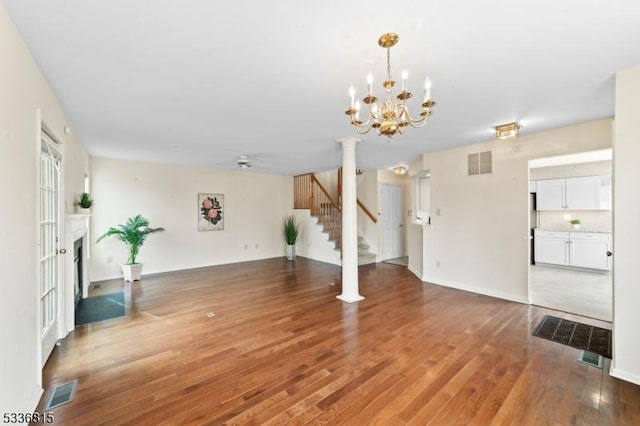 unfurnished living room with wood-type flooring and ceiling fan with notable chandelier