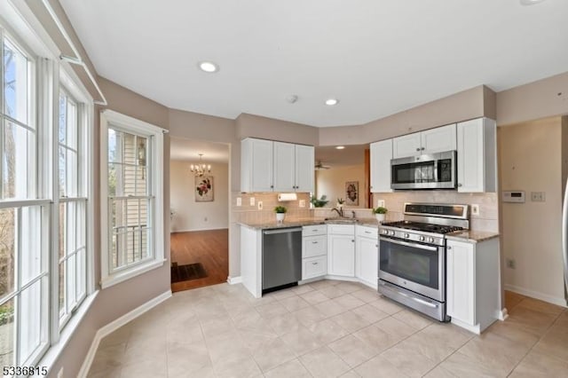 kitchen featuring stainless steel appliances, white cabinetry, sink, and light stone counters