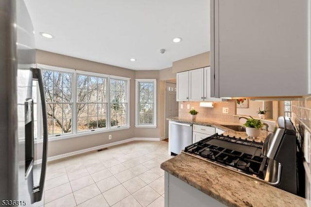 kitchen featuring sink, backsplash, white cabinets, light stone counters, and stainless steel appliances