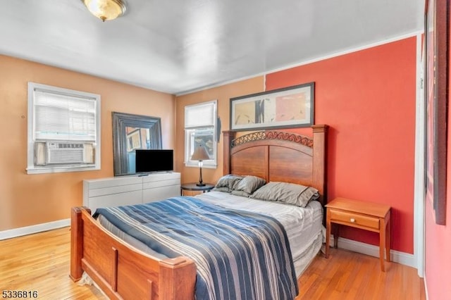 bedroom with cooling unit and light hardwood / wood-style floors