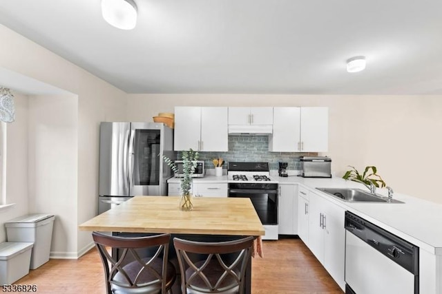 kitchen featuring under cabinet range hood, white cabinetry, stainless steel appliances, and light countertops