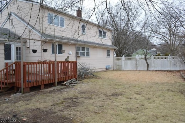 rear view of house featuring a wooden deck and a lawn