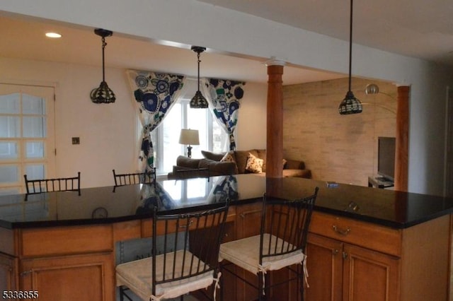 kitchen featuring ornate columns, a kitchen island, pendant lighting, and a kitchen breakfast bar