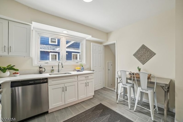 kitchen featuring wood finish floors, a sink, white cabinetry, light countertops, and dishwasher