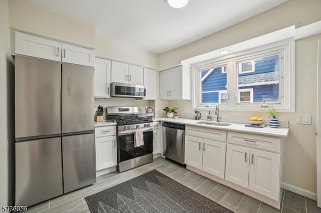 kitchen with white cabinets, stainless steel appliances, a sink, and light countertops