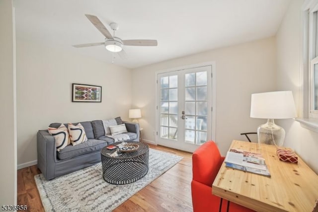 living area featuring ceiling fan, baseboards, wood finished floors, and french doors