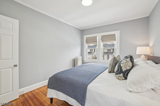 bedroom featuring baseboards, wood finished floors, and ornamental molding