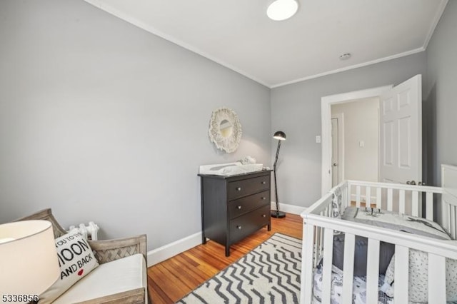 bedroom with light wood-style floors, baseboards, and ornamental molding