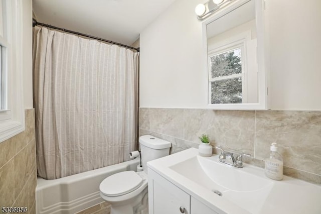 bathroom with toilet, a wainscoted wall, shower / tub combo, vanity, and tile walls