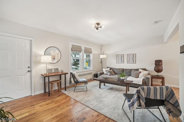 living room with radiator, light wood-style floors, and baseboards