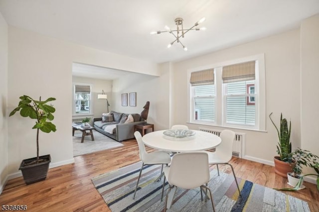 dining space featuring baseboards, light wood-type flooring, and a notable chandelier