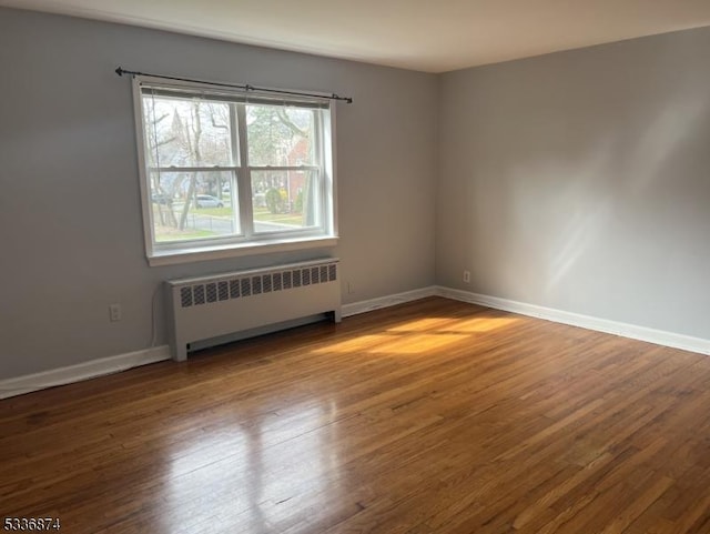 spare room with radiator heating unit and wood-type flooring