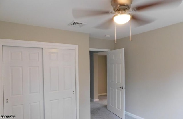 unfurnished bedroom with ceiling fan, light carpet, and a closet