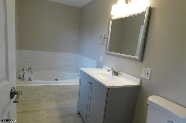 bathroom with vanity, tiled bath, and toilet