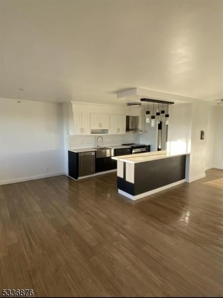 kitchen with wall chimney range hood, backsplash, dark wood-type flooring, and white cabinets