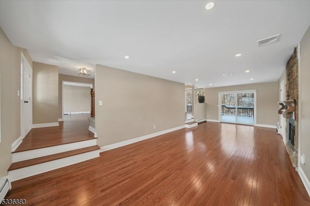 unfurnished living room with a baseboard radiator, hardwood / wood-style floors, and a fireplace