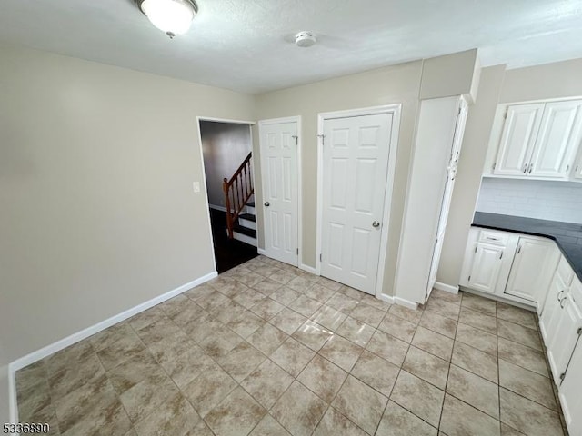 interior space with tasteful backsplash, white cabinetry, and light tile patterned floors