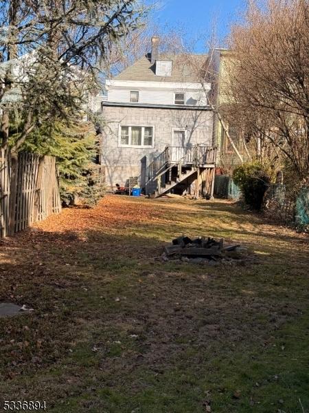 rear view of property featuring stairs and fence