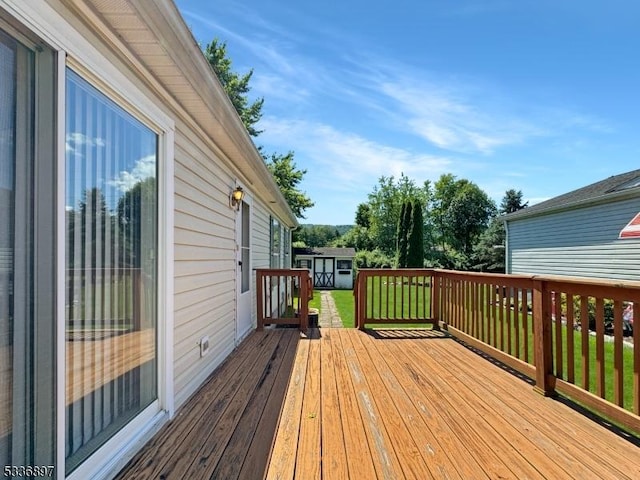 wooden terrace with a storage shed and a lawn