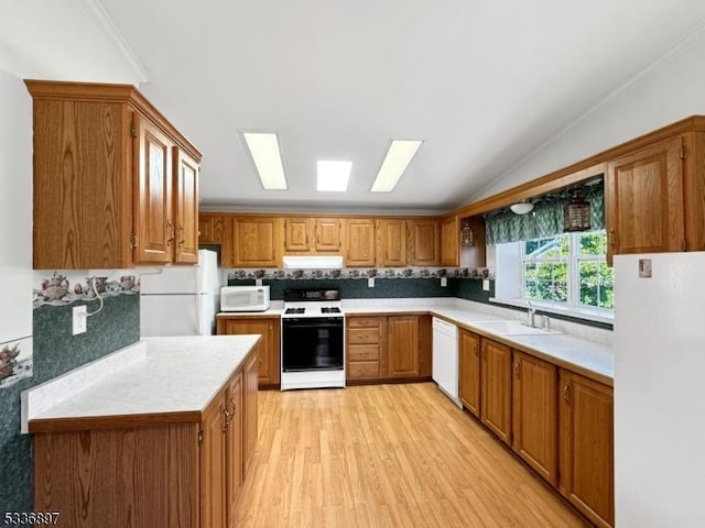 kitchen featuring sink, white appliances, light hardwood / wood-style flooring, vaulted ceiling with skylight, and decorative backsplash