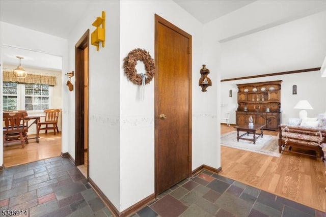 hallway featuring baseboards and stone tile floors