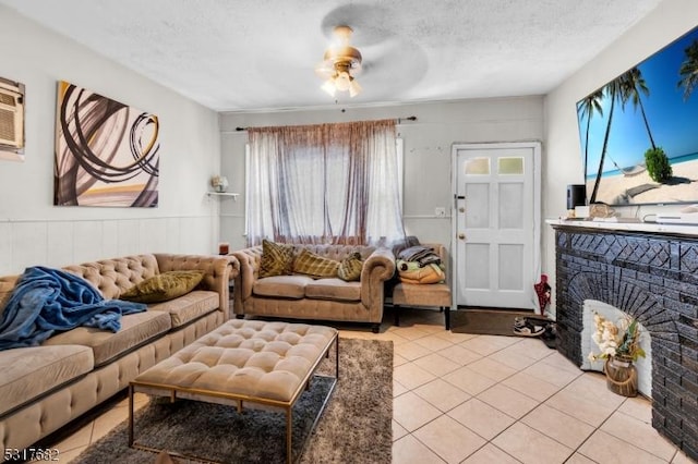 tiled living room with ceiling fan, a fireplace, a textured ceiling, and a wealth of natural light