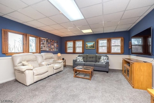 carpeted living room featuring a drop ceiling