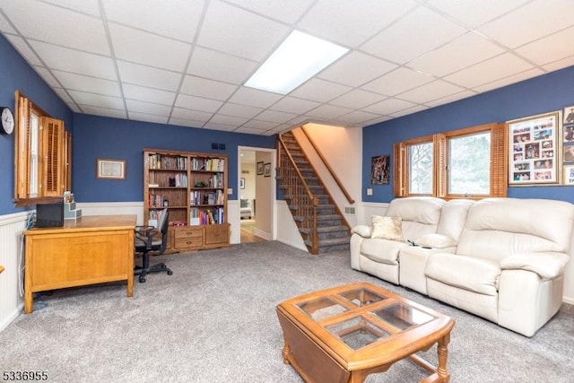 living room with a paneled ceiling and carpet