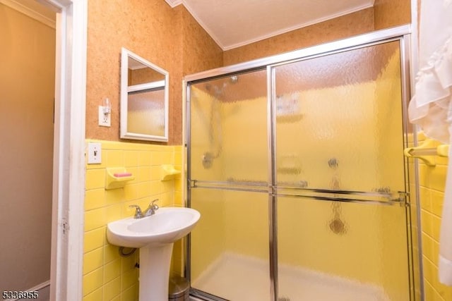 bathroom with crown molding, an enclosed shower, sink, and tile walls